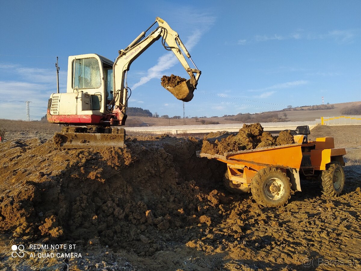 Yellow excavator and dump truck loading soil on rural construction site under clear blue sky.